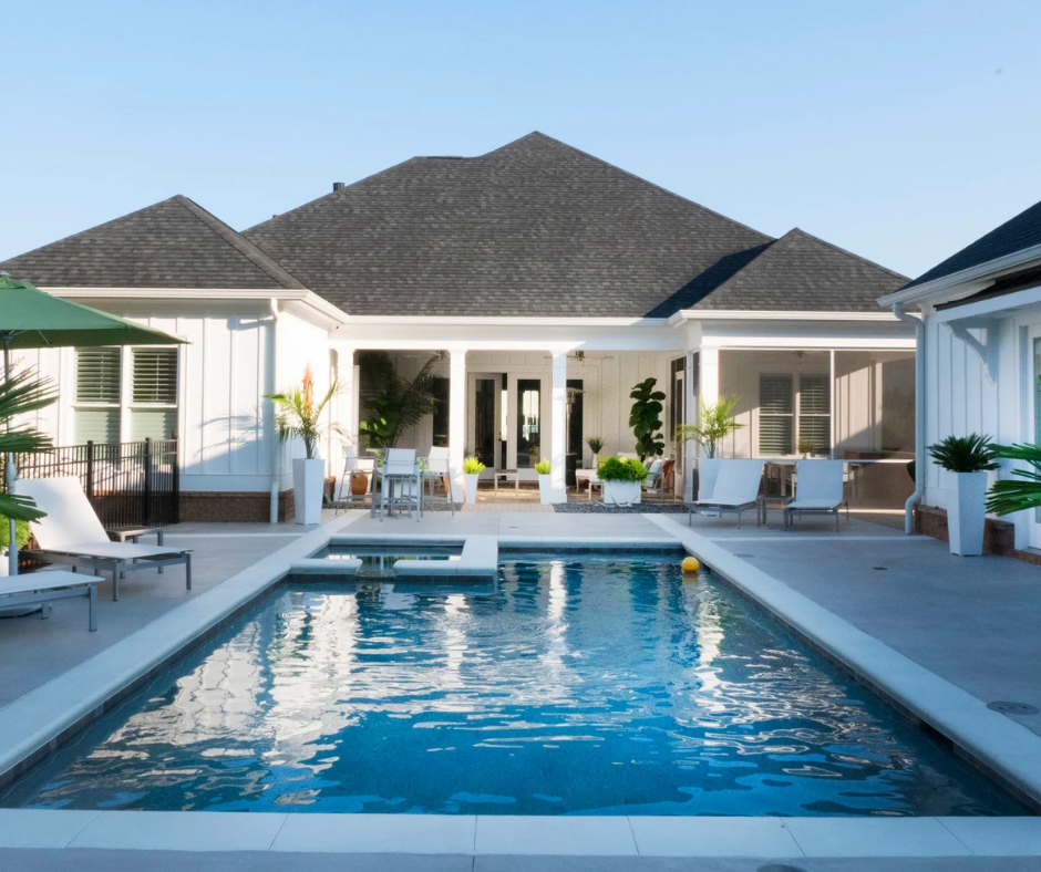 A white house with a large swimming pool in front of it