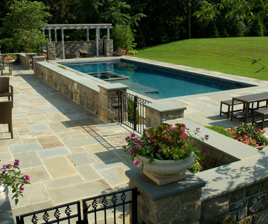 A large swimming pool is surrounded by a stone walllu