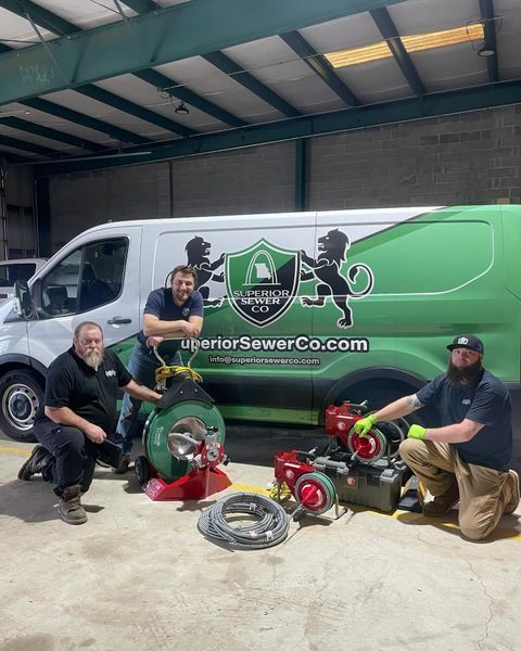 Four men, sewer company crew, pose with tools and van. Green and white van, logo 
