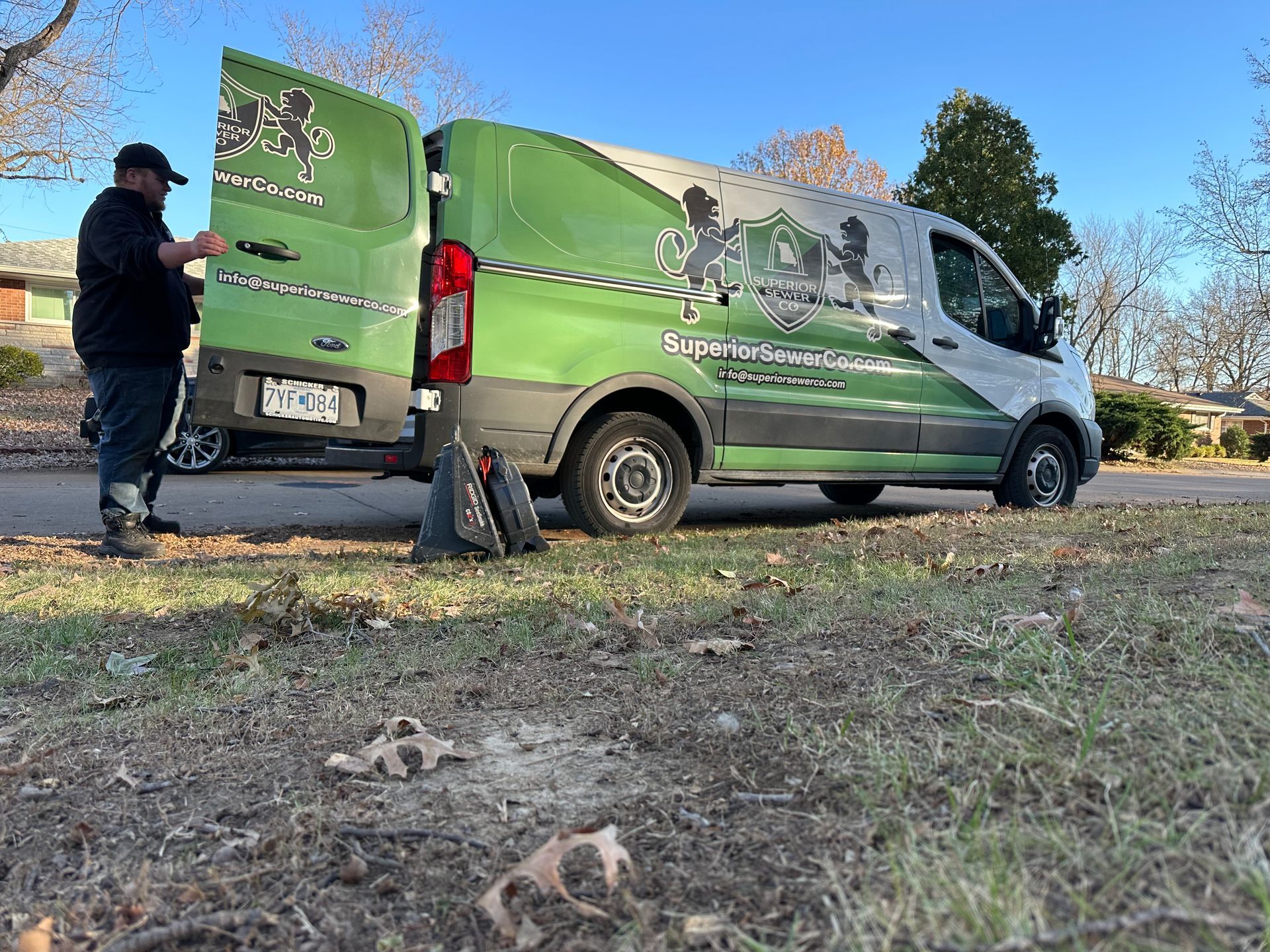 Man at a green and white van with open doors on a residential street.