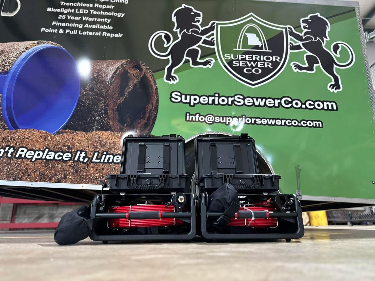 Two black sewer inspection robots in front of a green truck with logo 