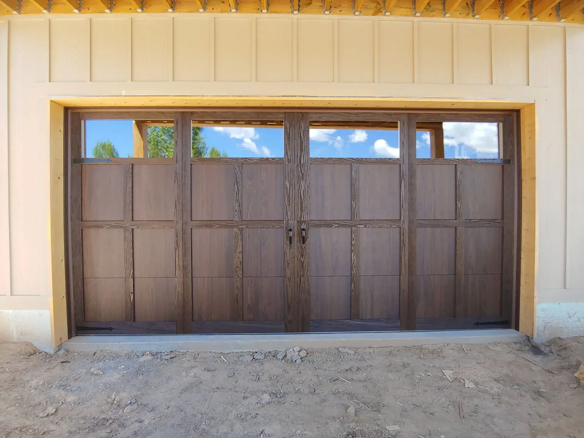 Brown wooden garage door with glass windows, set in a light-colored frame.