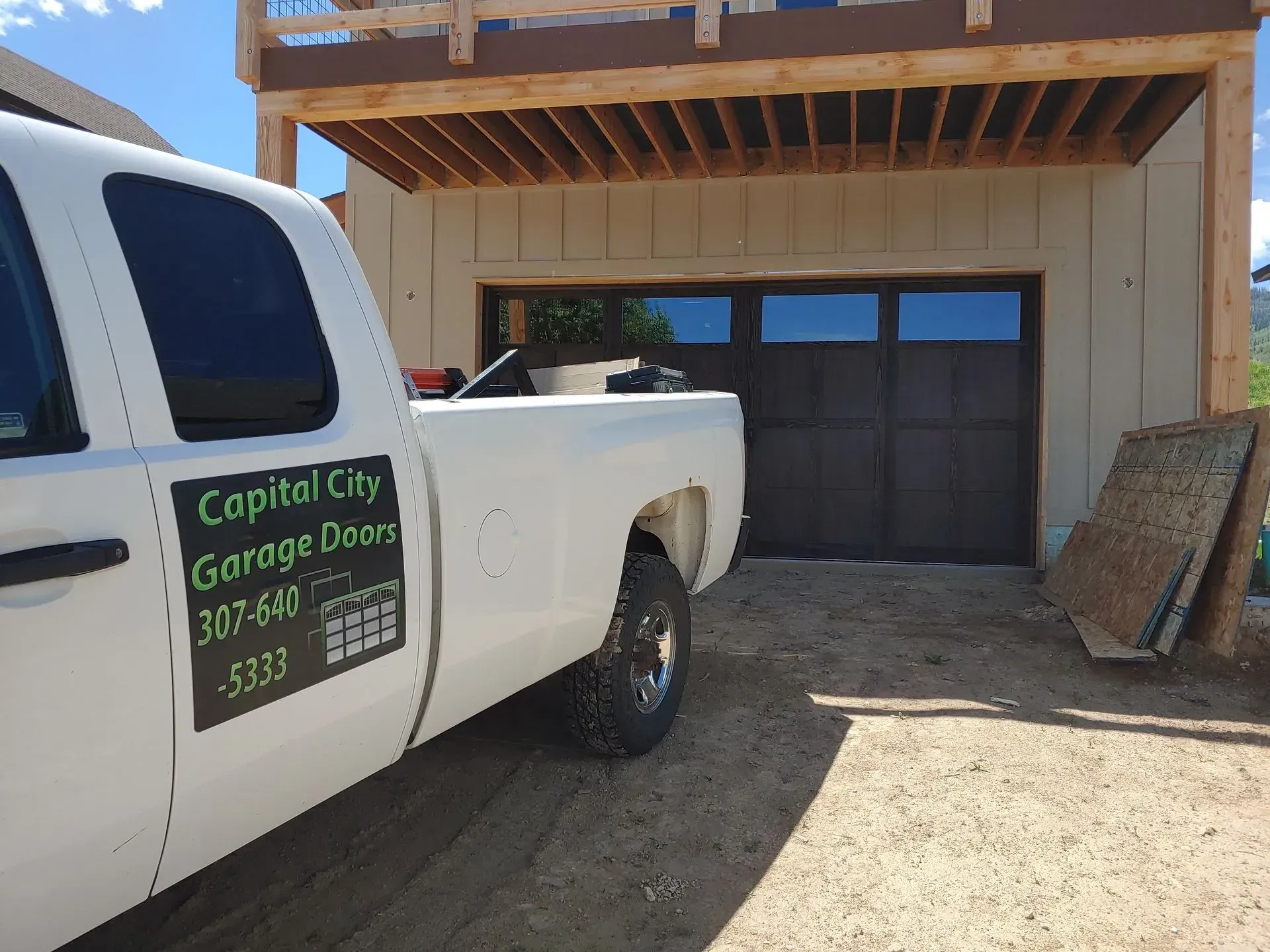 White truck parked in front of a new garage door, Capital City Garage Co. logo on truck door.