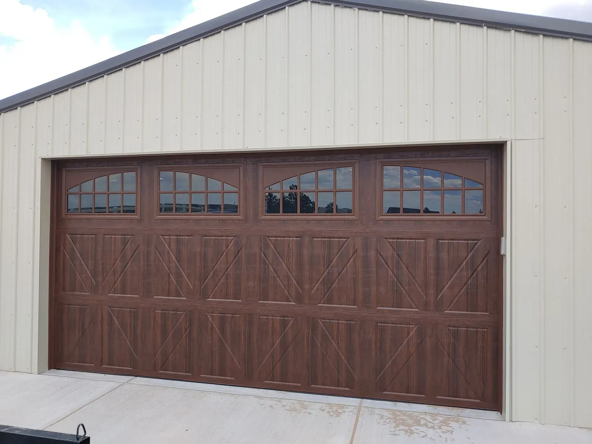 Brown garage door with arched windows, light-colored building with a concrete floor.
