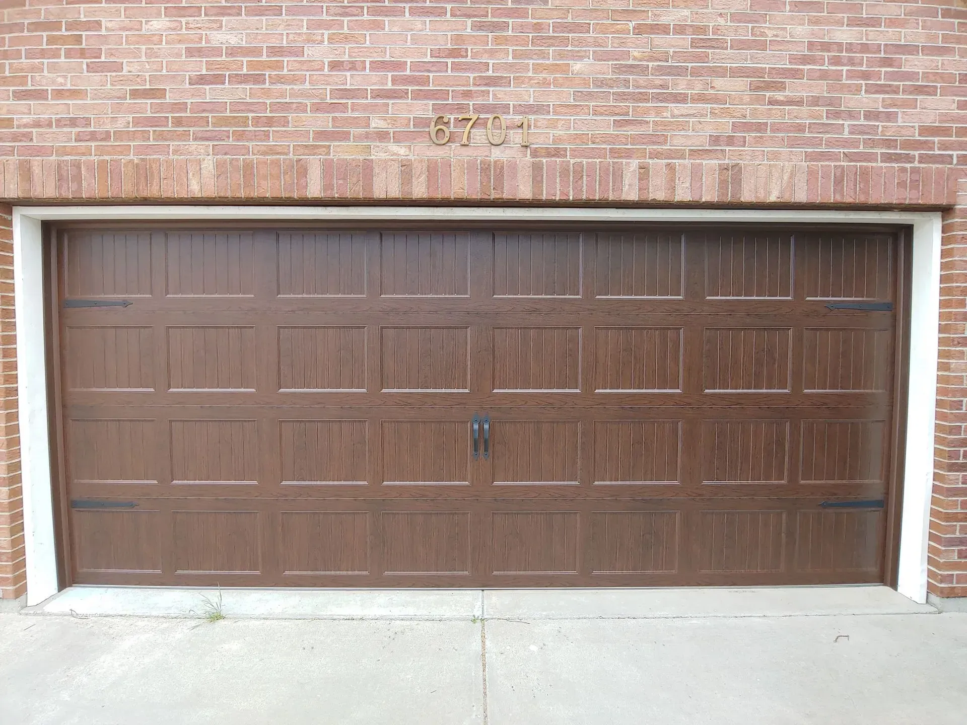 Brown garage door with brick exterior.