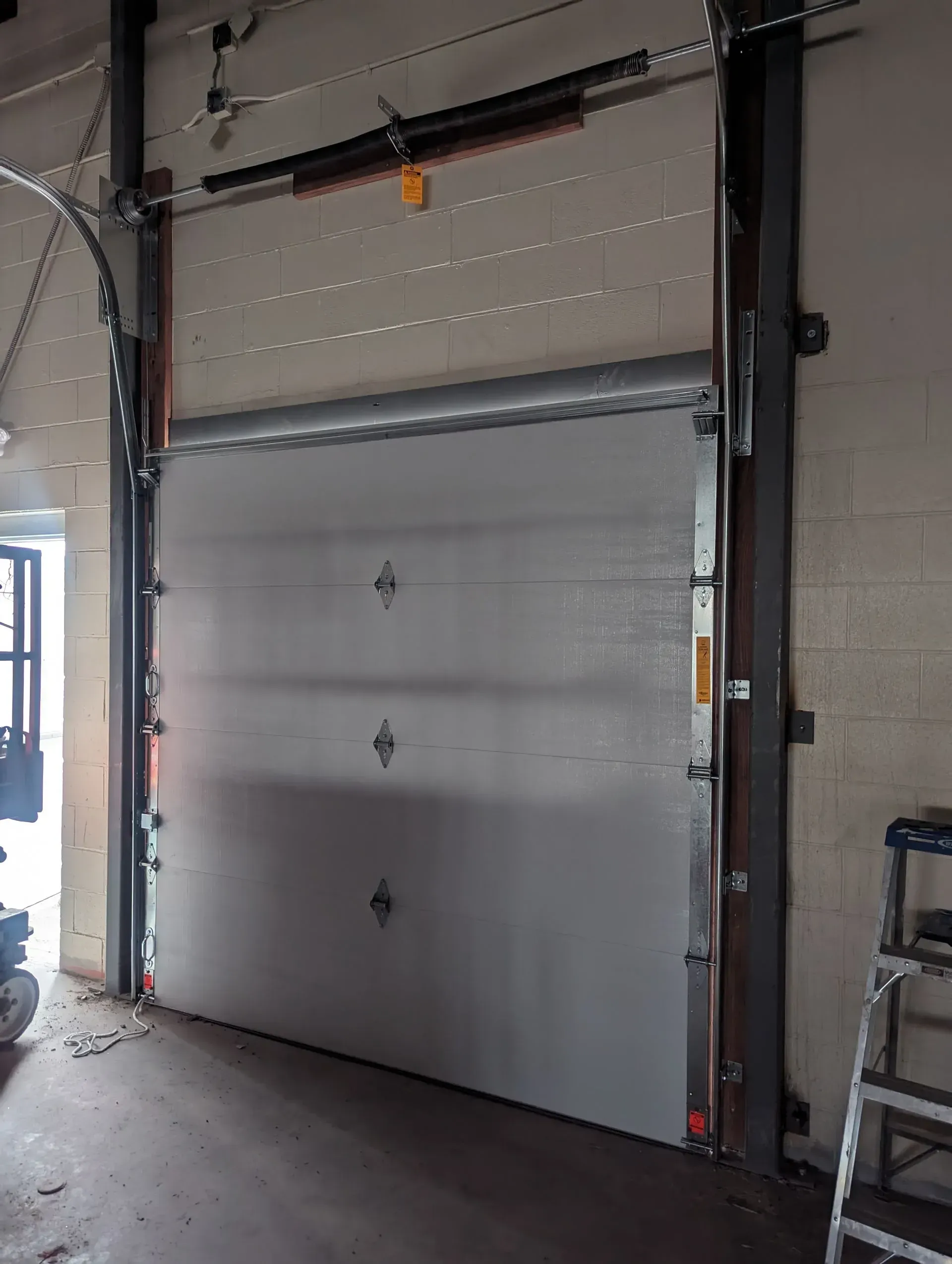 Gray industrial overhead door in a concrete and brick building.