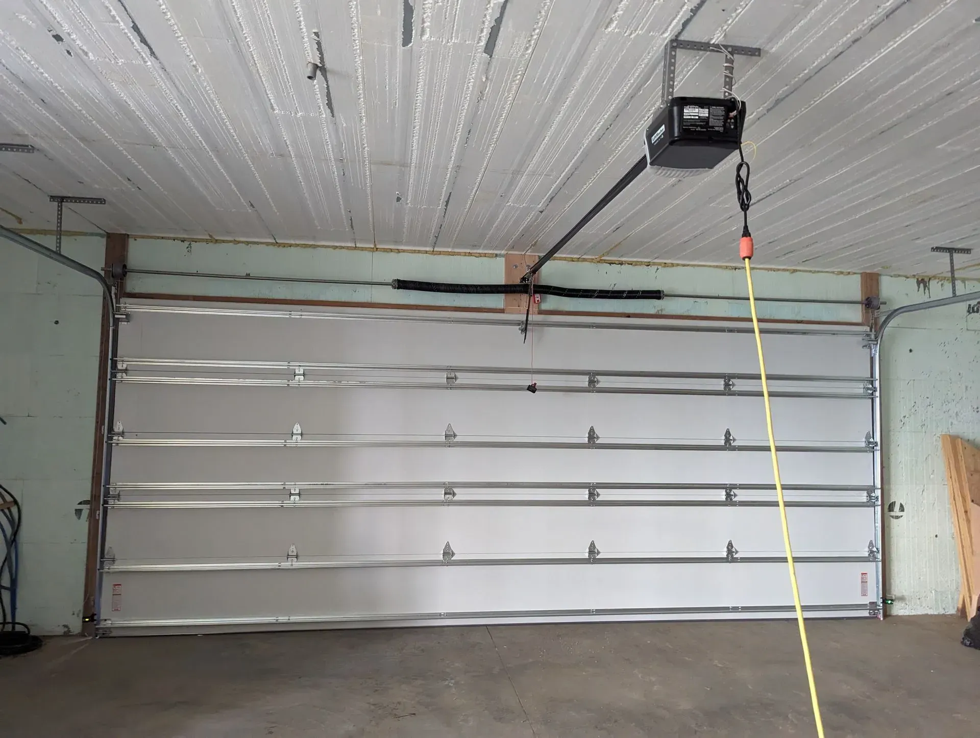 Closed silver garage door with an overhead opener, inside a garage.