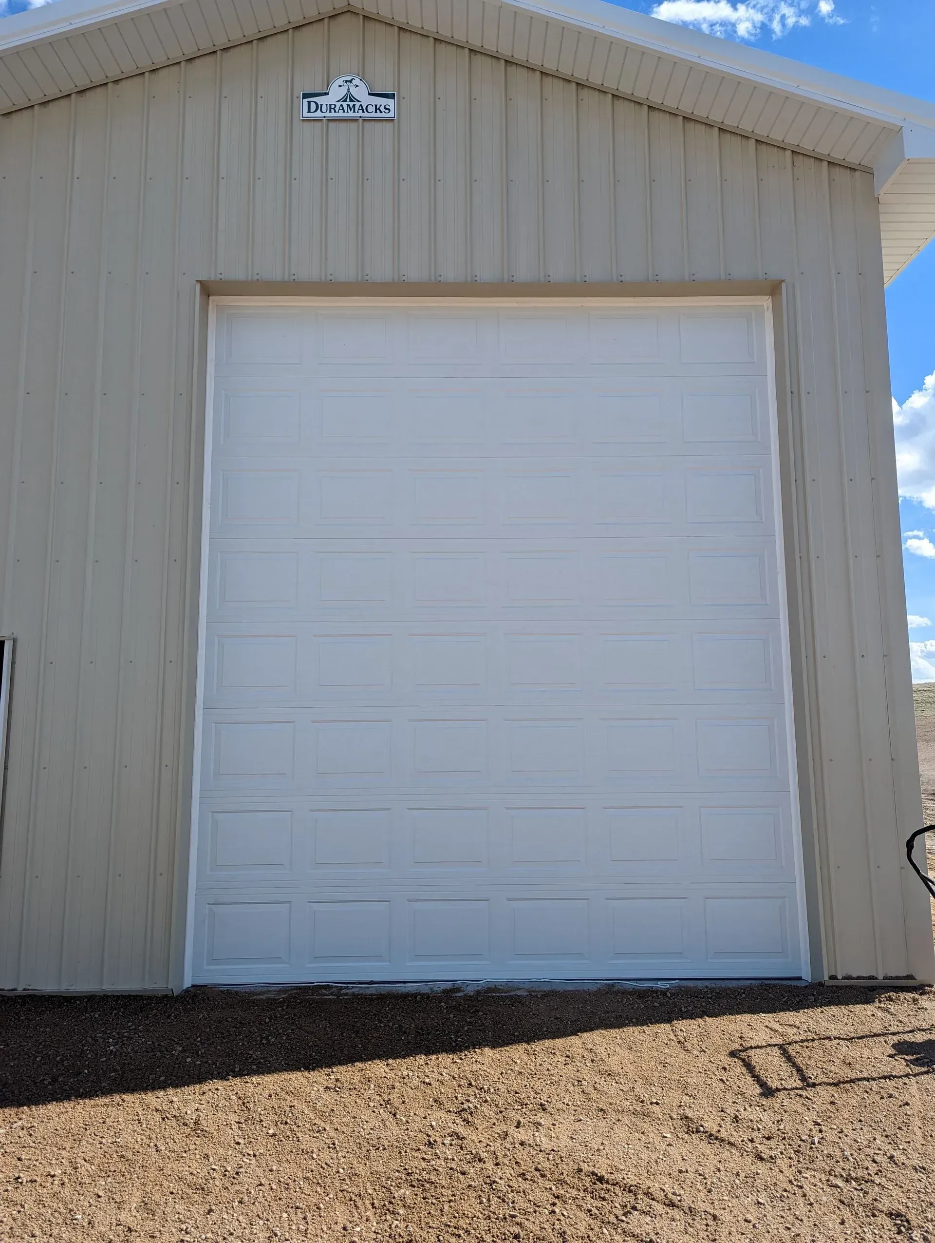 Tan building with a closed white garage door. Blue sky visible.