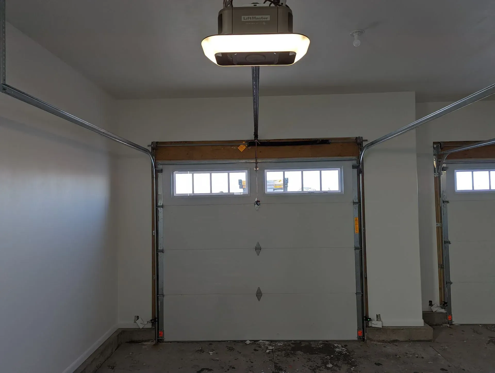 White garage door inside a garage, with an opener overhead.