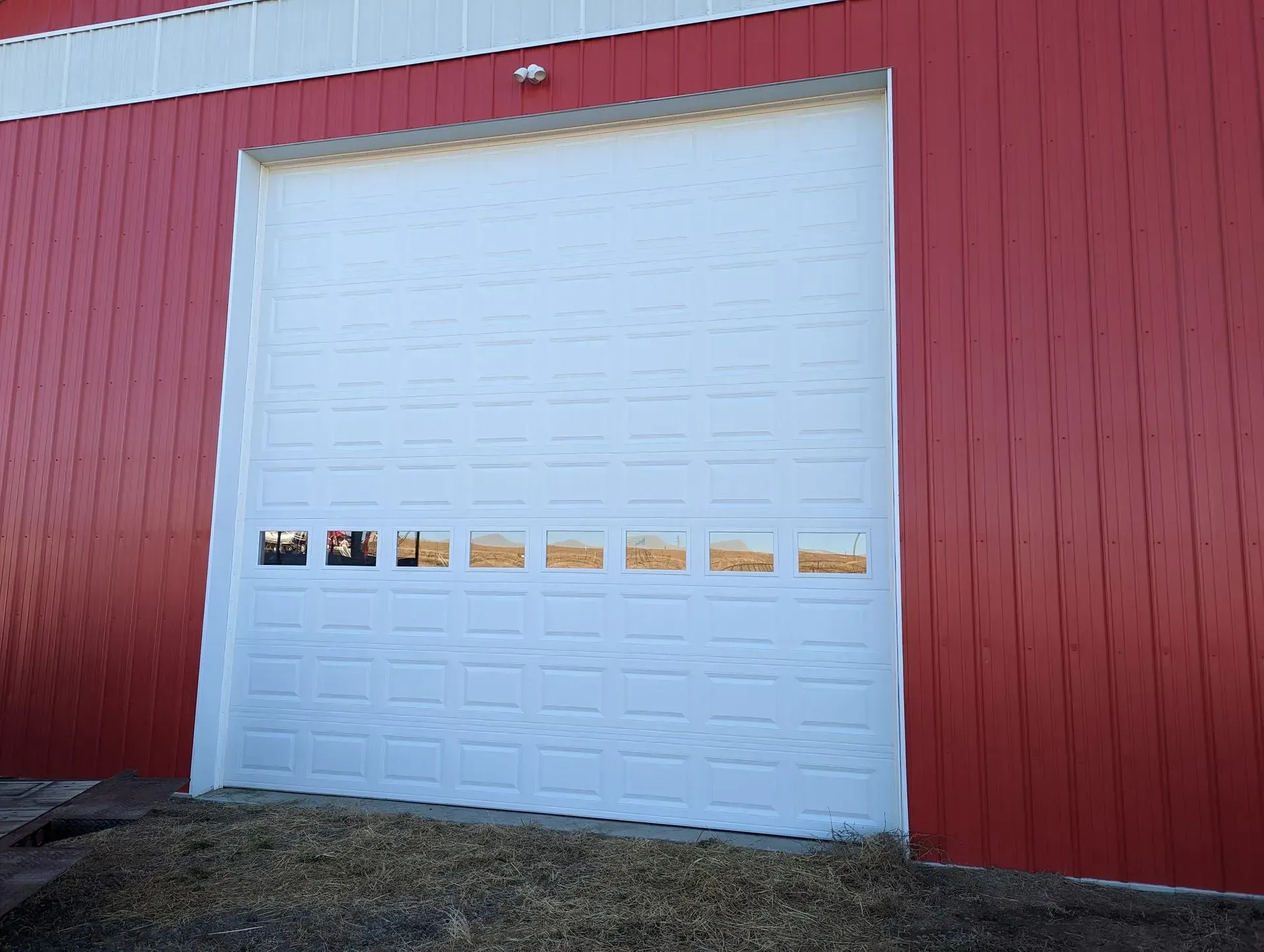 White garage door on red building with small windows.