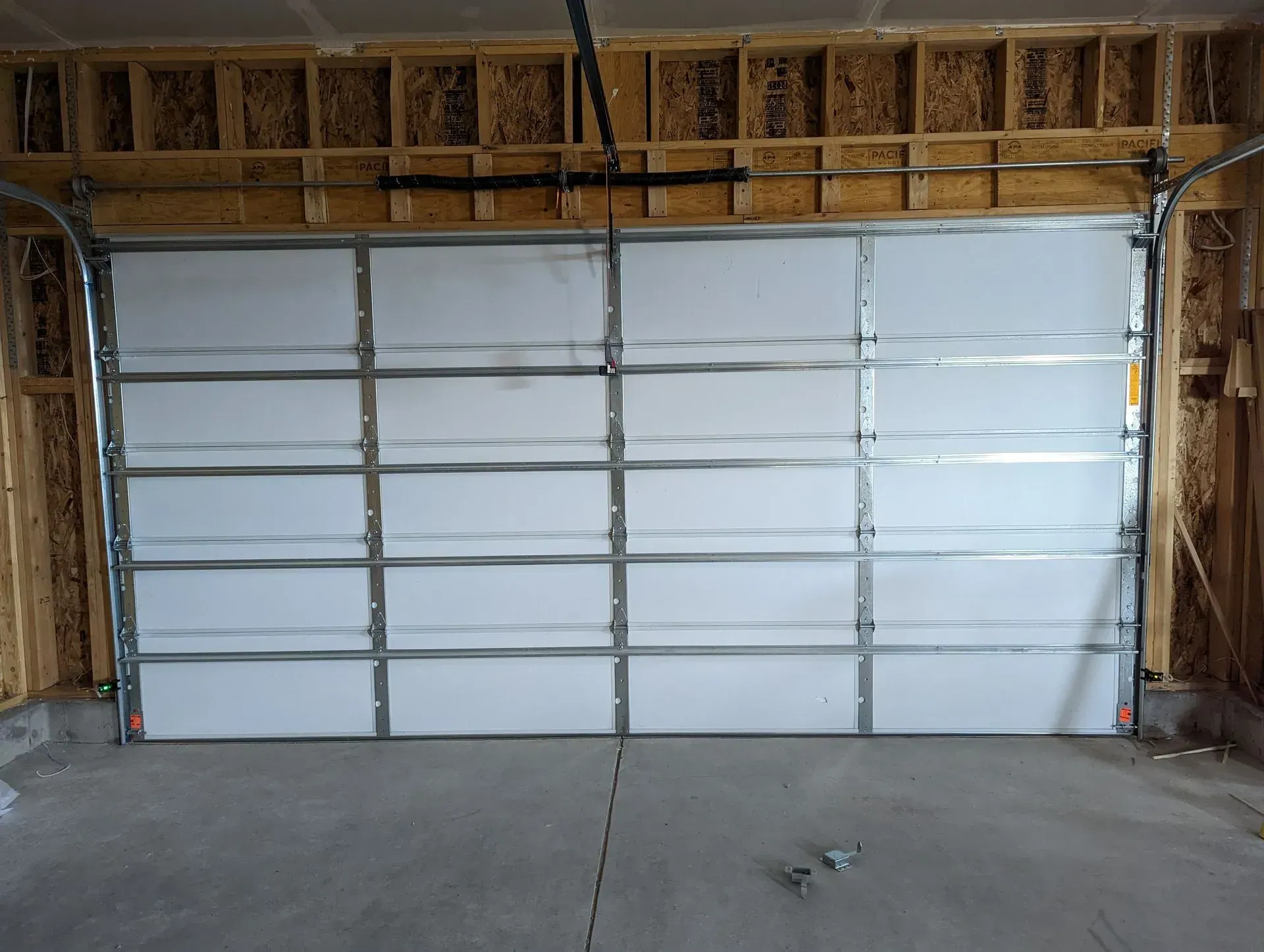 White garage door inside unfinished garage.