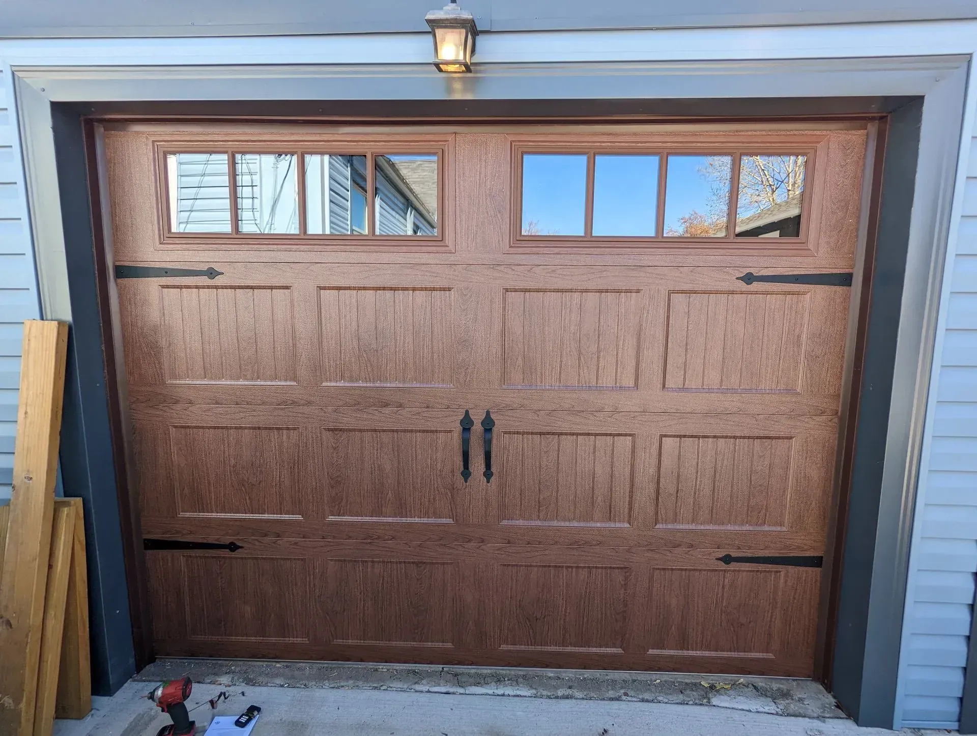 Brown garage door with windows, hardware, and light fixture, set in a garage frame.