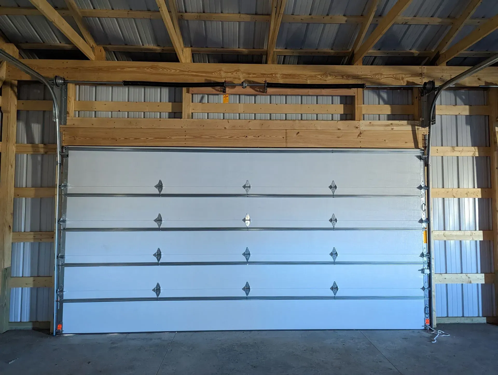 White garage door inside a wooden-framed structure, open.