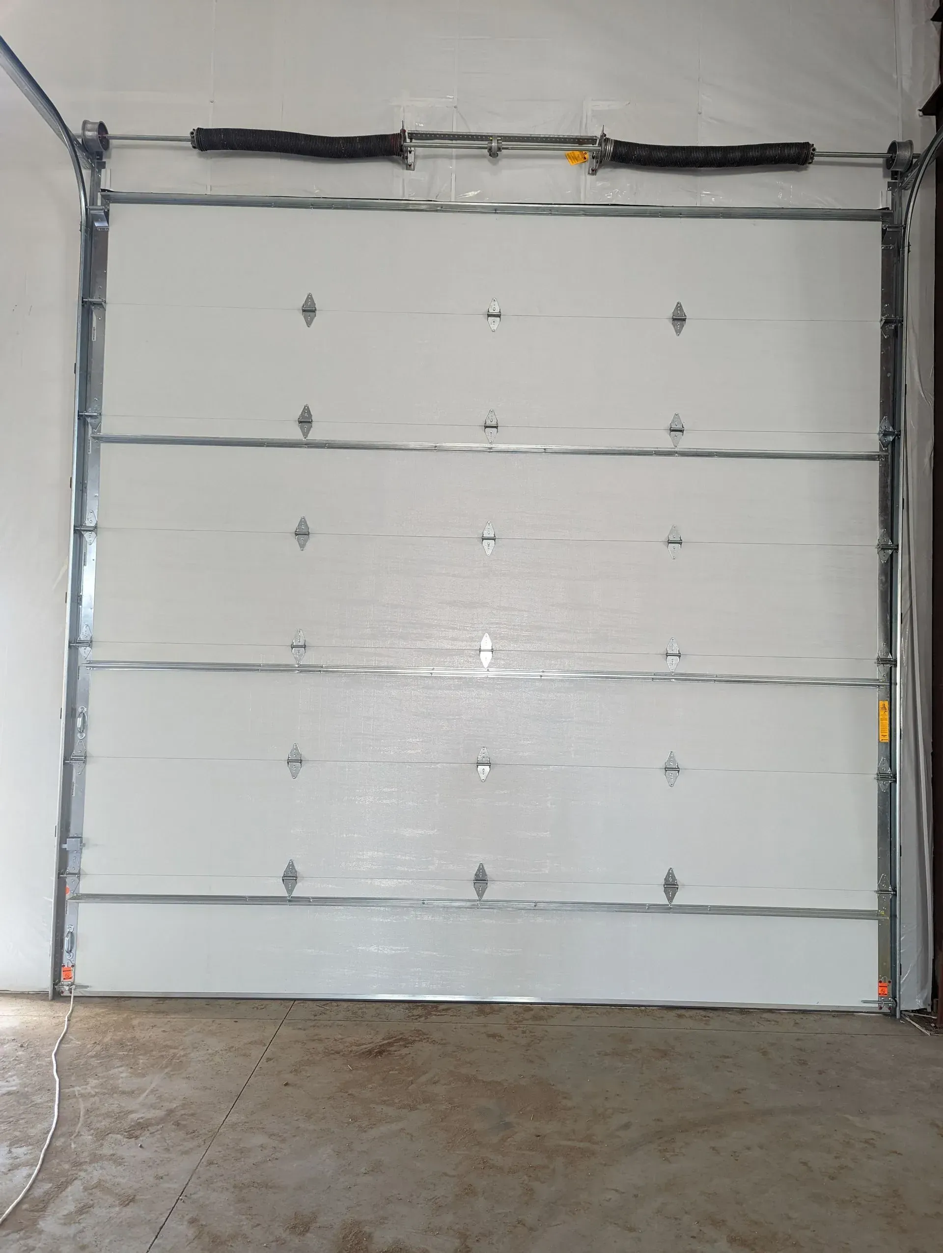 White, sectional garage door with metal framing. Inside view.