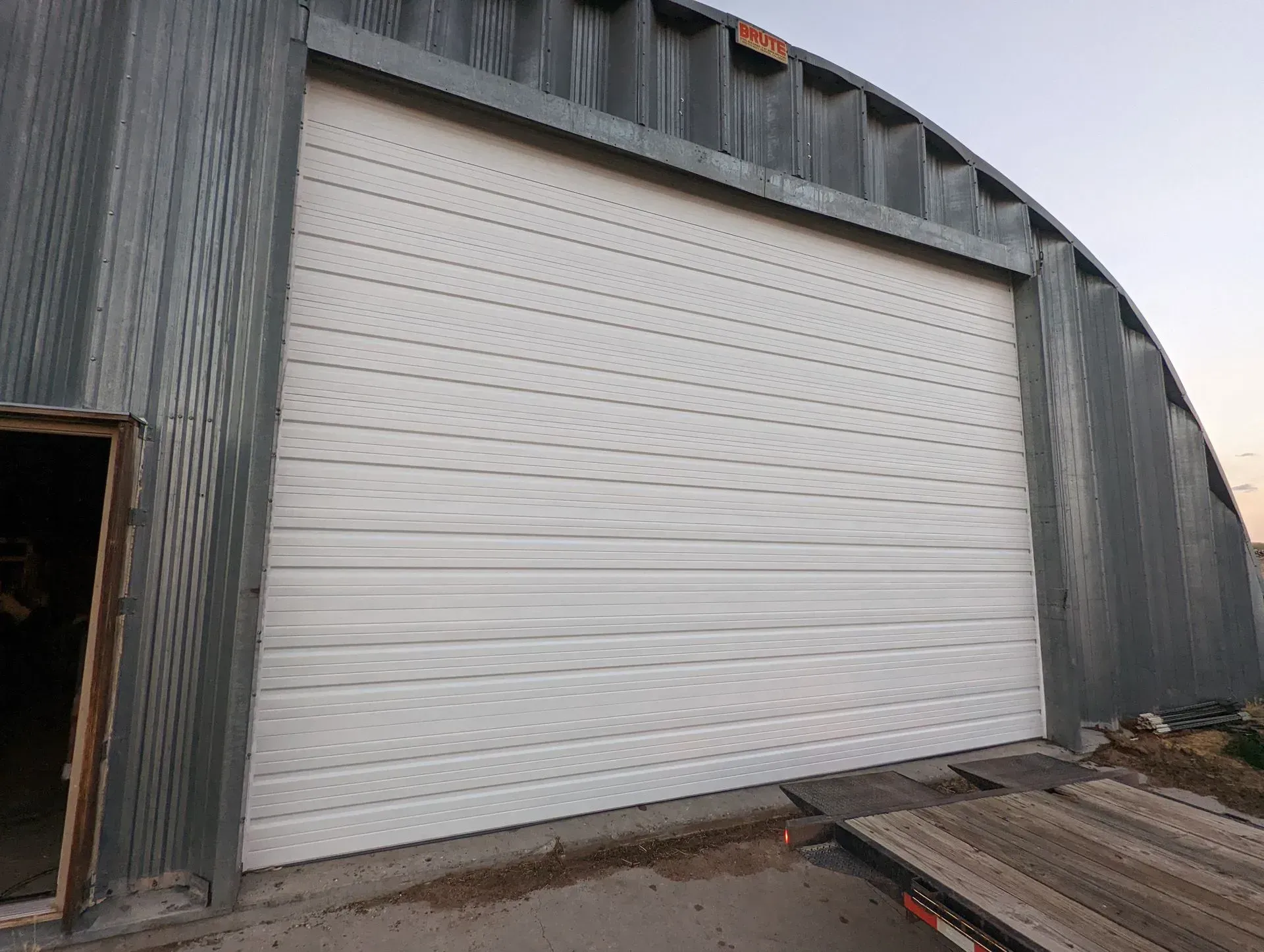 White garage door on a corrugated metal building with an arched roof.