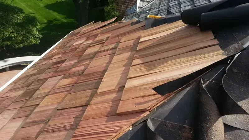 Close-up of a damaged roof with missing shingles and exposed underlayment, showing repair work in progress