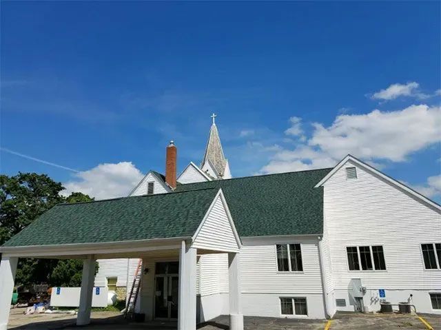 White church building with green roof and steeple under a blue sky