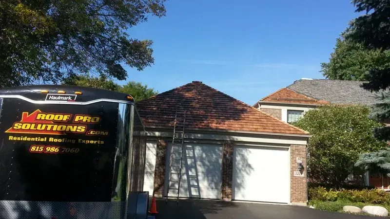 Brick house with white garage door and a black service van parked in the driveway.
