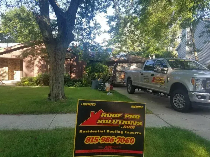 Roof Pro Solutions yard sign in front of a house, with a service truck parked nearby.