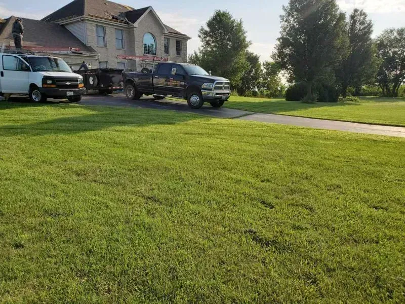 Suburban house with two parked trucks beside a green lawn on a sunny day