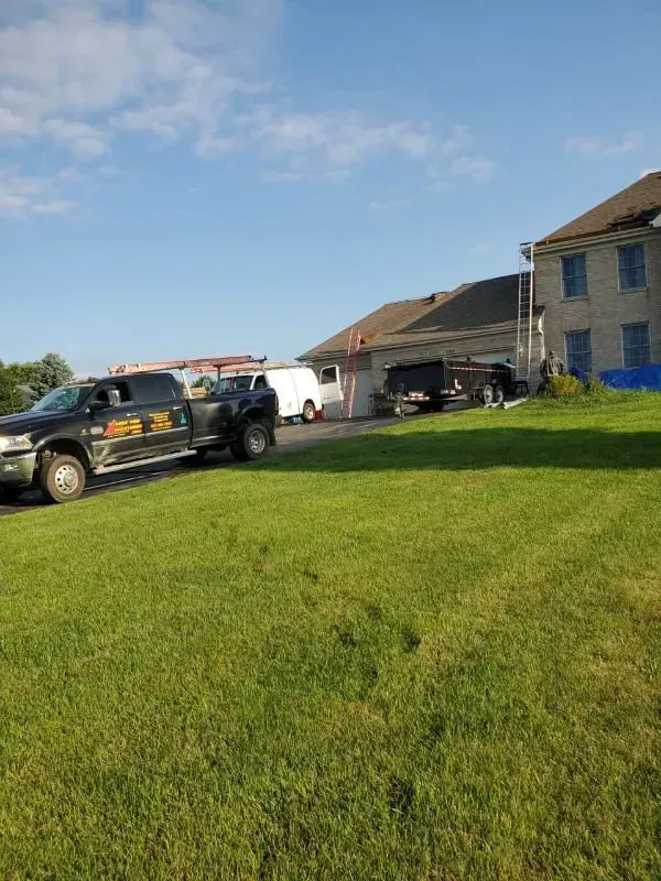 Black service van parked on a grassy lawn beside a house under a blue sky