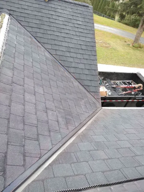 Roof shingles with a steep gable and a rooftop equipment unit near the edge.
