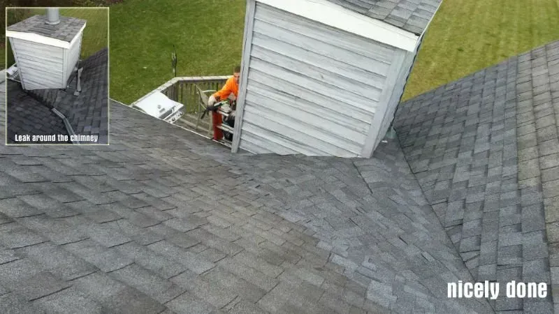 Steep gray shingled roof with a white dormer and a worker in orange near the edge under repair