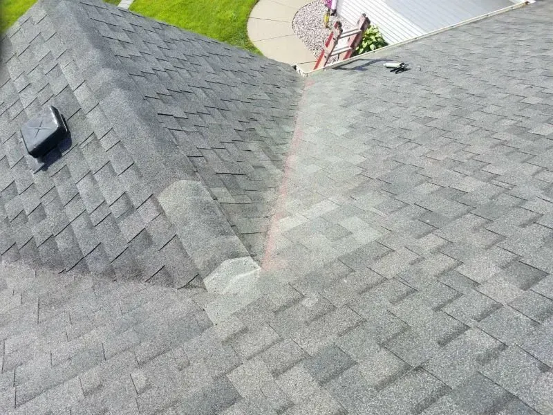 Gray shingled roof with a small dormer window and satellite dish in the background