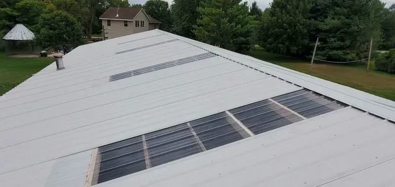 White rooftop with solar panels on a house in a green suburban neighborhood.