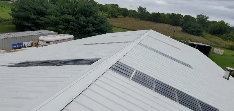 White industrial roof with solar panels in a rural landscape