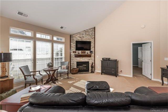 A living room with a couch, chairs, table, fireplace and television.