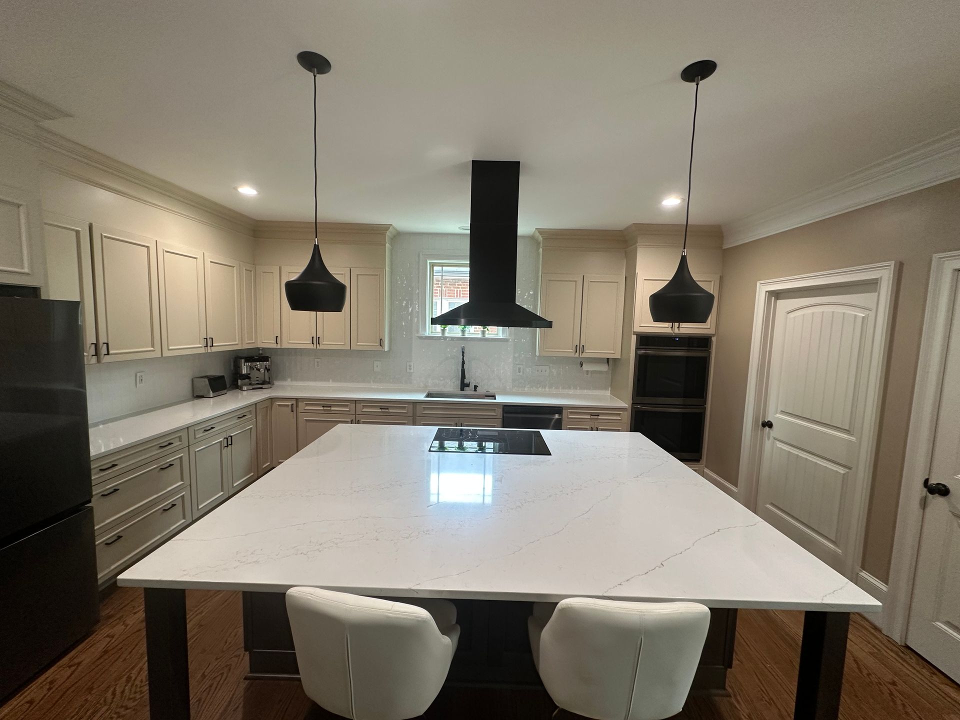 A kitchen with white cabinets and a large island in the middle.