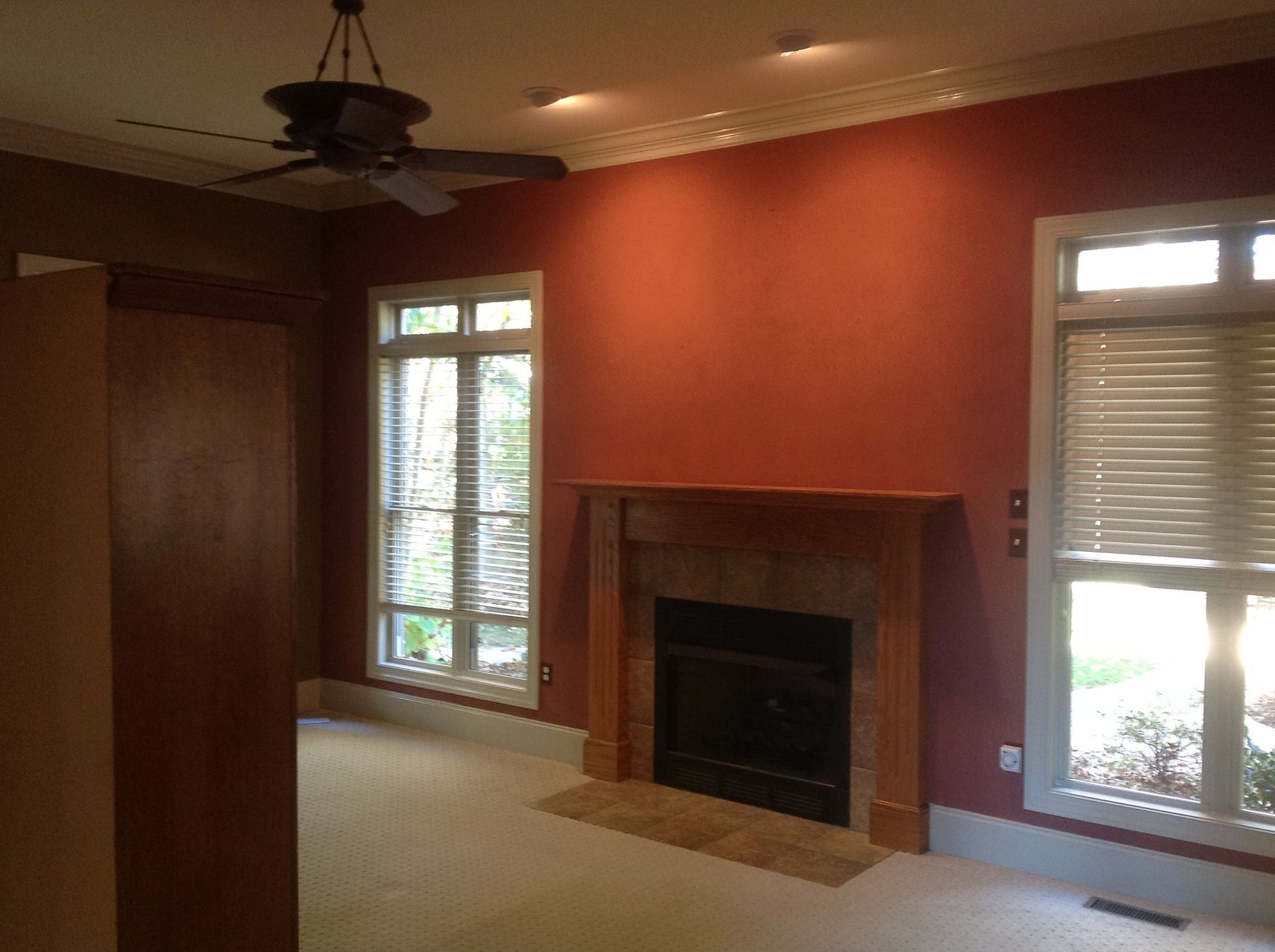 An empty room with a fireplace and a ceiling fan