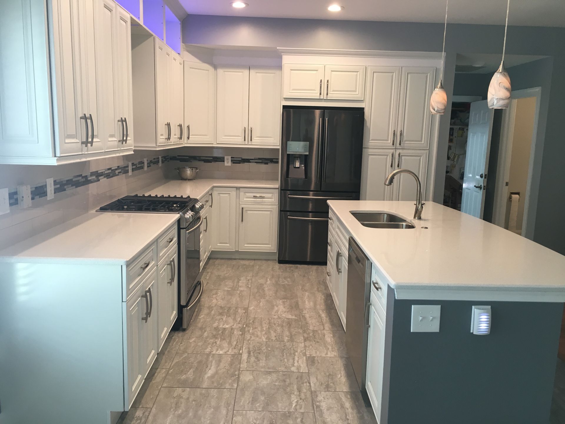 A kitchen with white cabinets , stainless steel appliances , and a large island.
