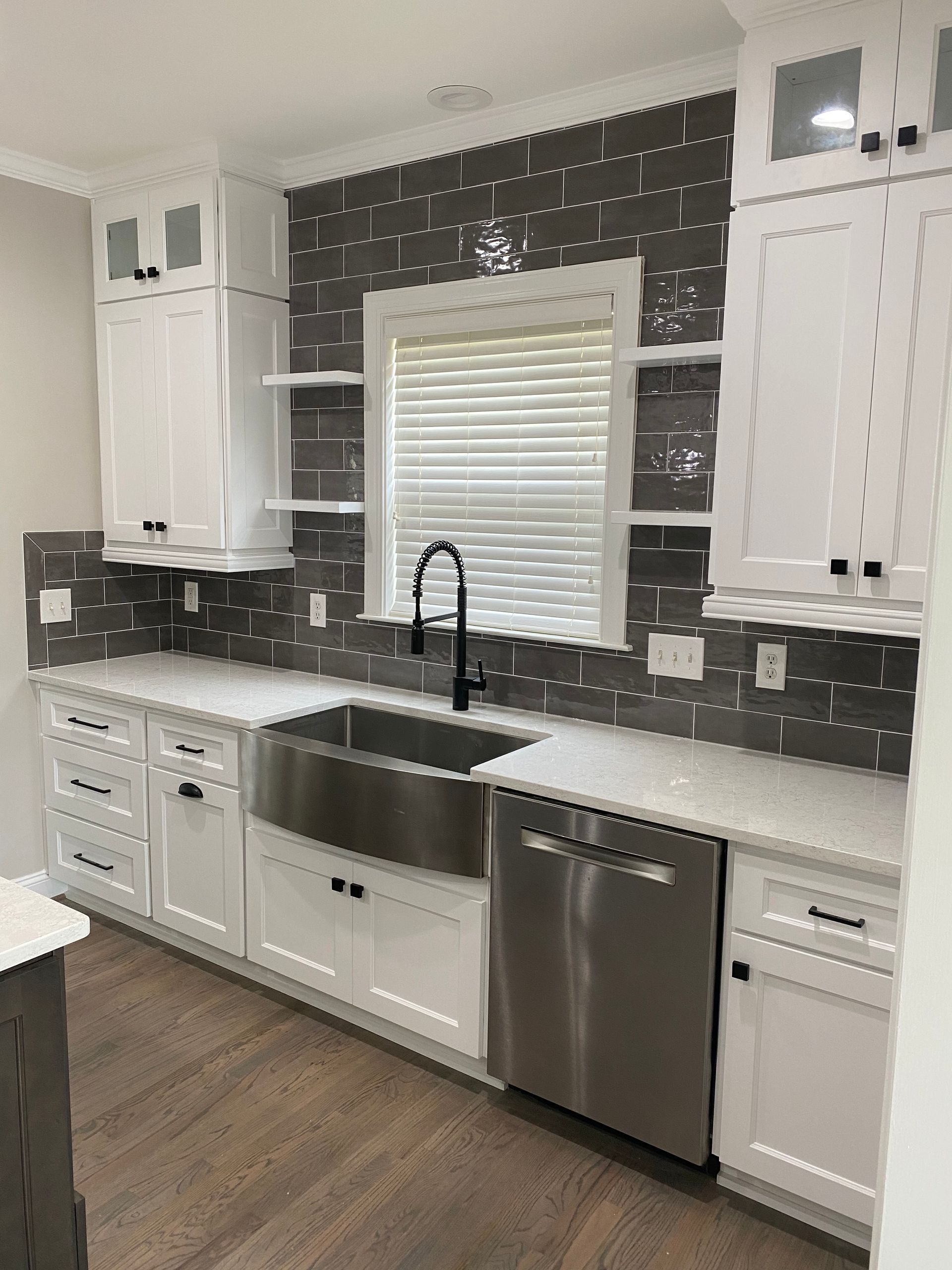 A kitchen with white cabinets , stainless steel appliances , a sink , and a window.