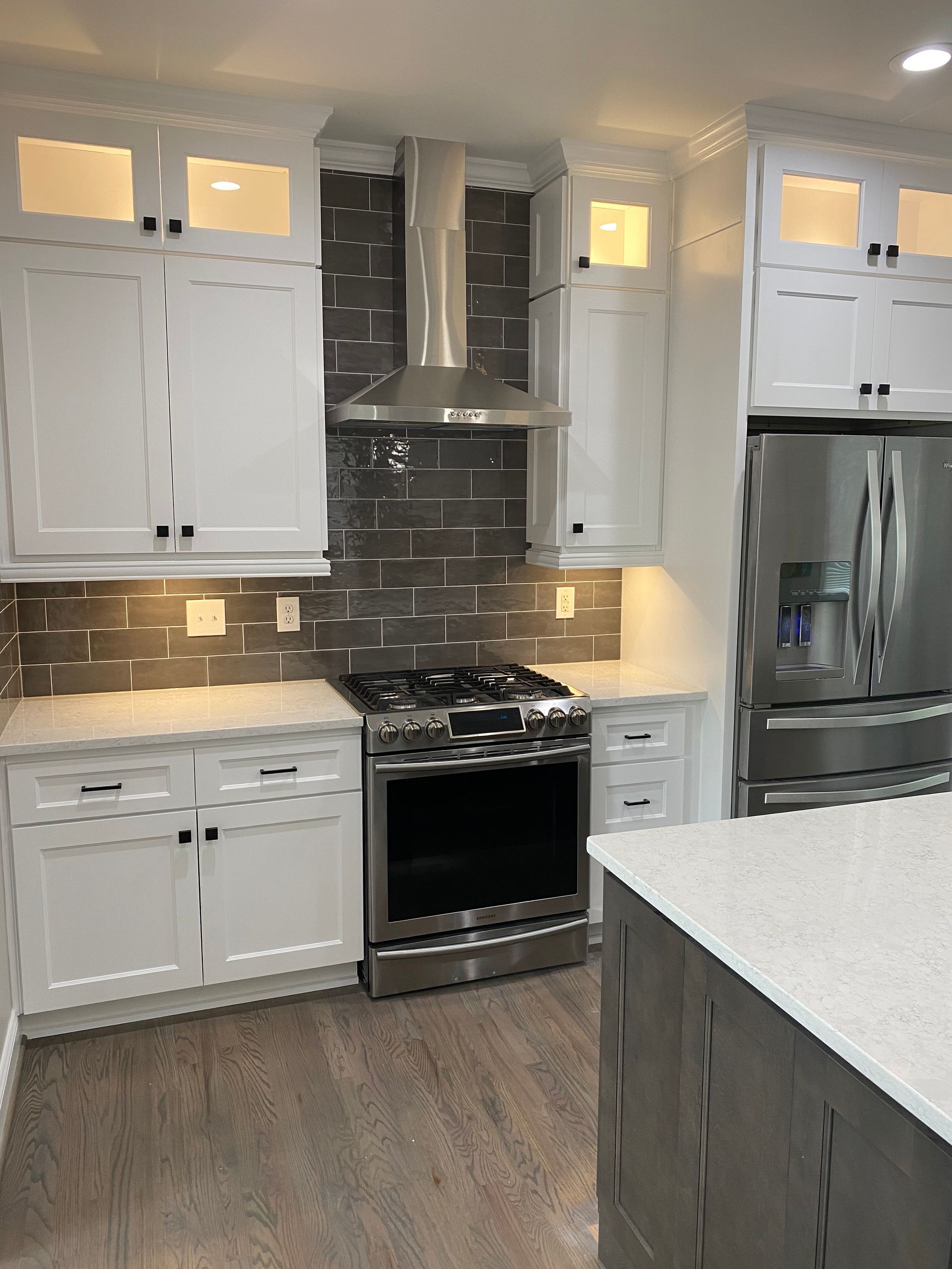 A kitchen with white cabinets , stainless steel appliances , a stove and a refrigerator.