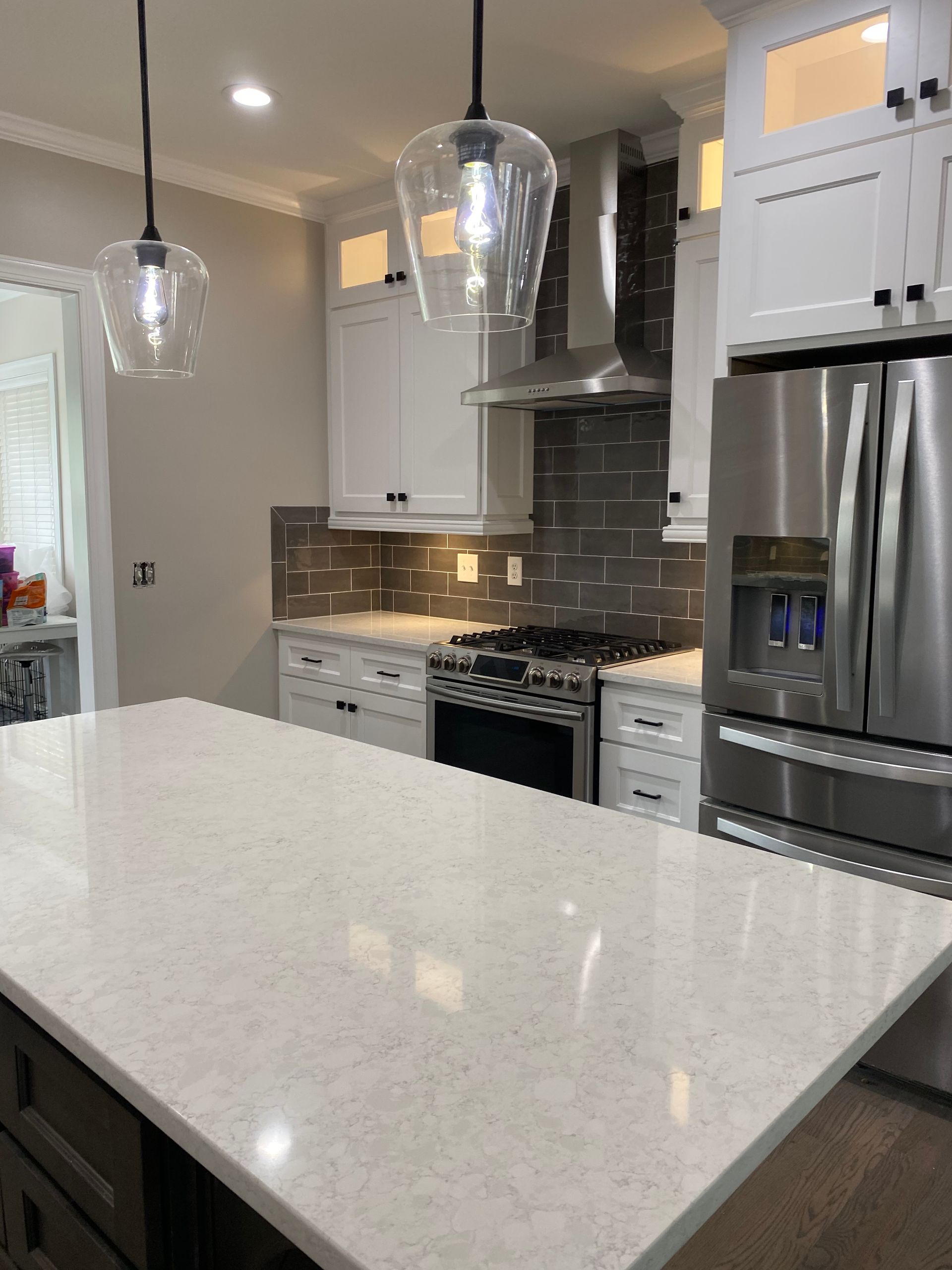A kitchen with white cabinets , stainless steel appliances , and a large island.
