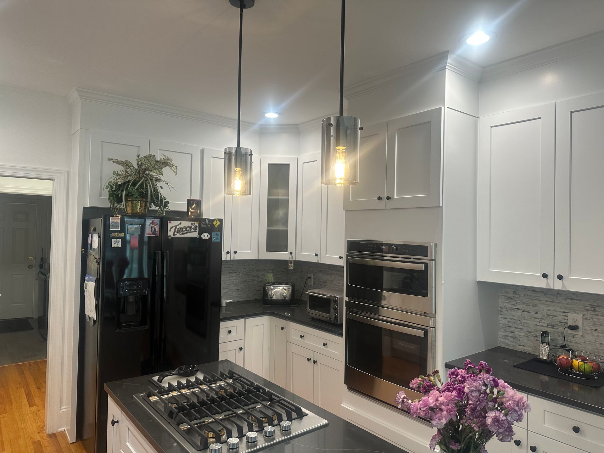 A kitchen with white cabinets , a black refrigerator and a stove top oven.