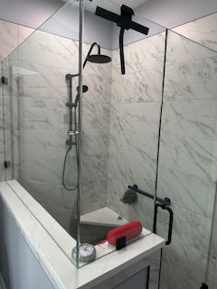 A bathroom with a walk in shower with a glass door and a shower head.