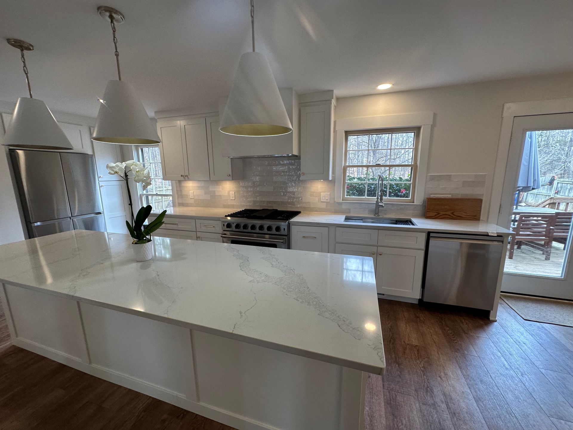 A kitchen with white cabinets , stainless steel appliances , and a large island.