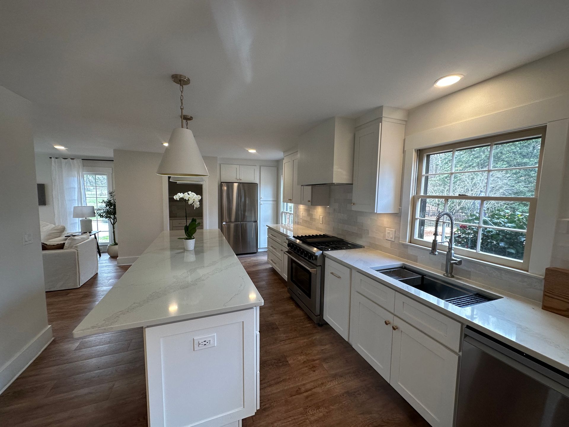 A kitchen with white cabinets , stainless steel appliances , and a large island.