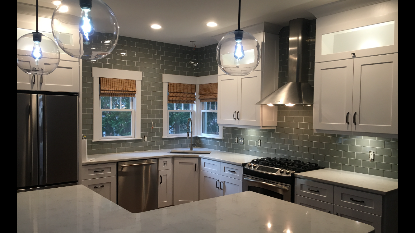 A kitchen with white cabinets , stainless steel appliances , and a large island.