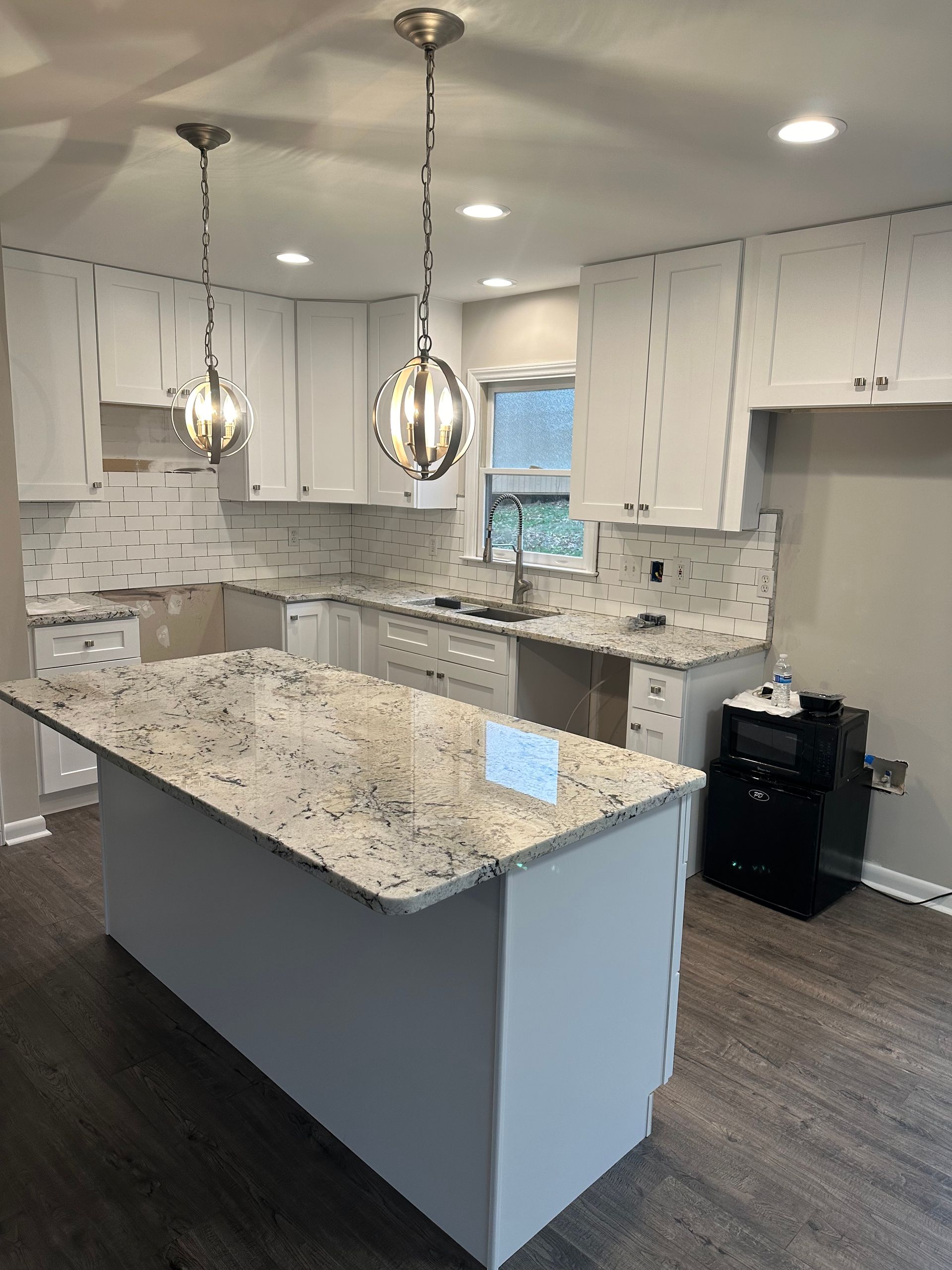 A kitchen with granite counter tops and white cabinets