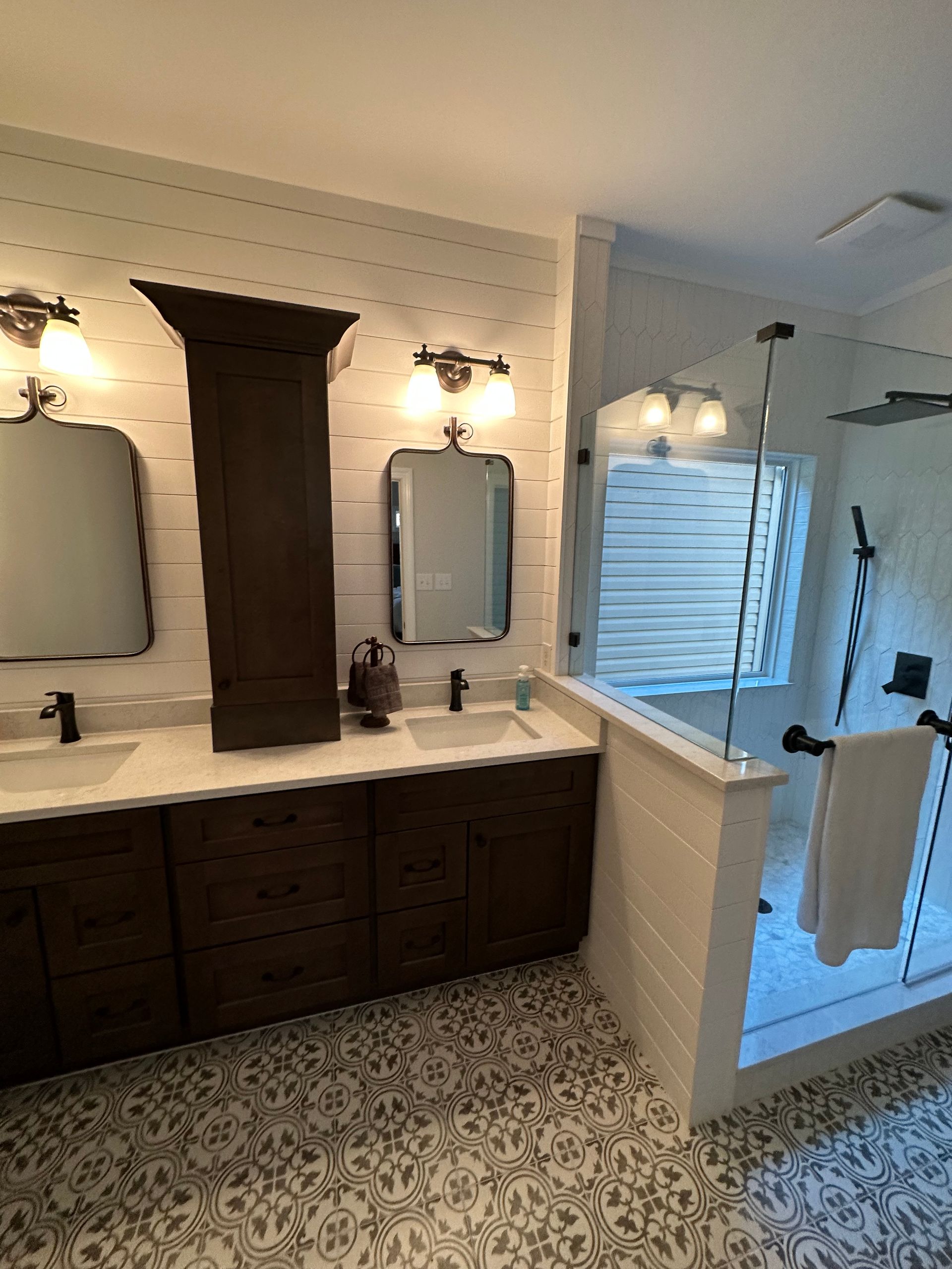 A bathroom with two sinks , two mirrors and a walk in shower.