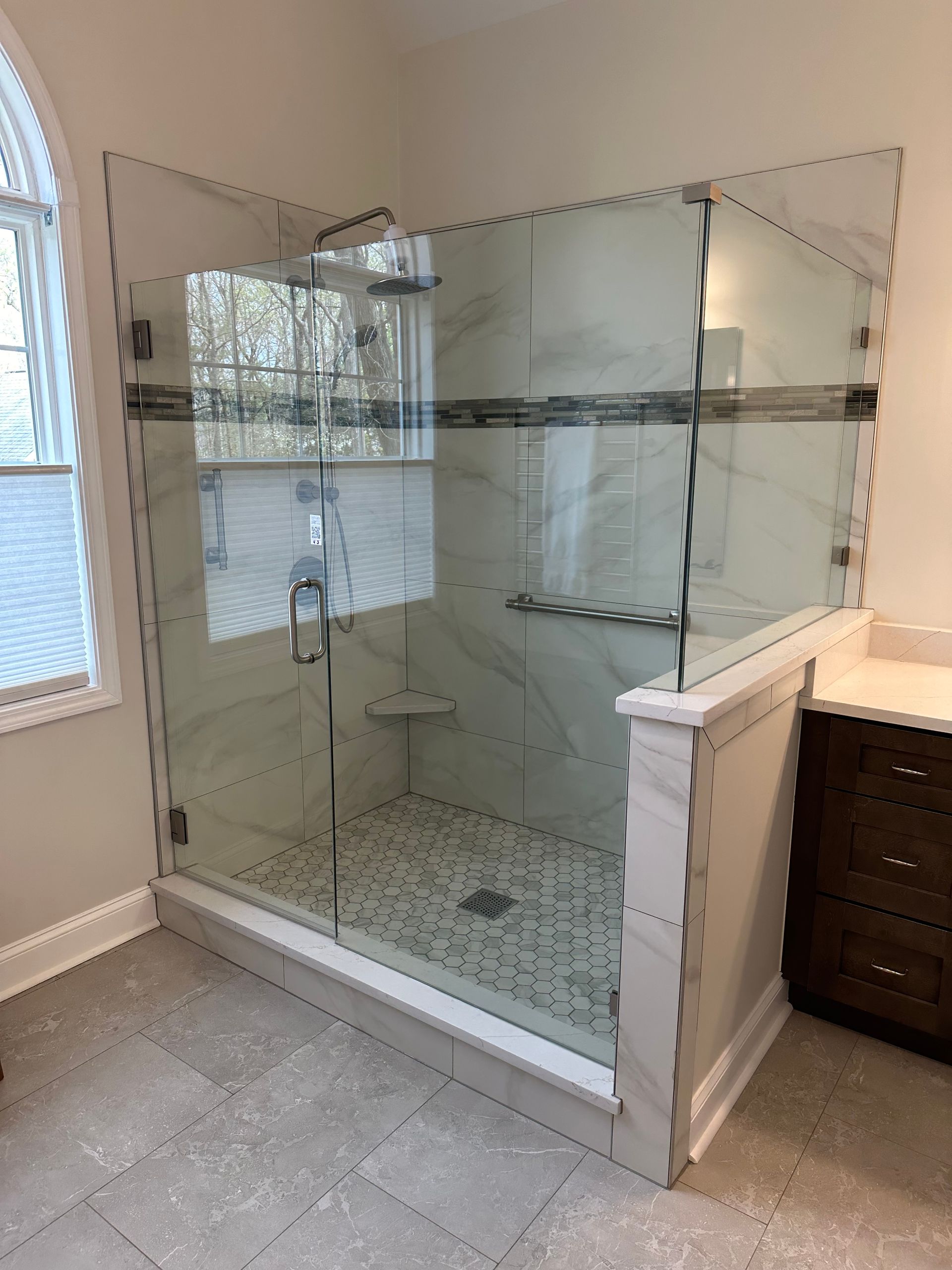 A bathroom with a walk in shower and a window.