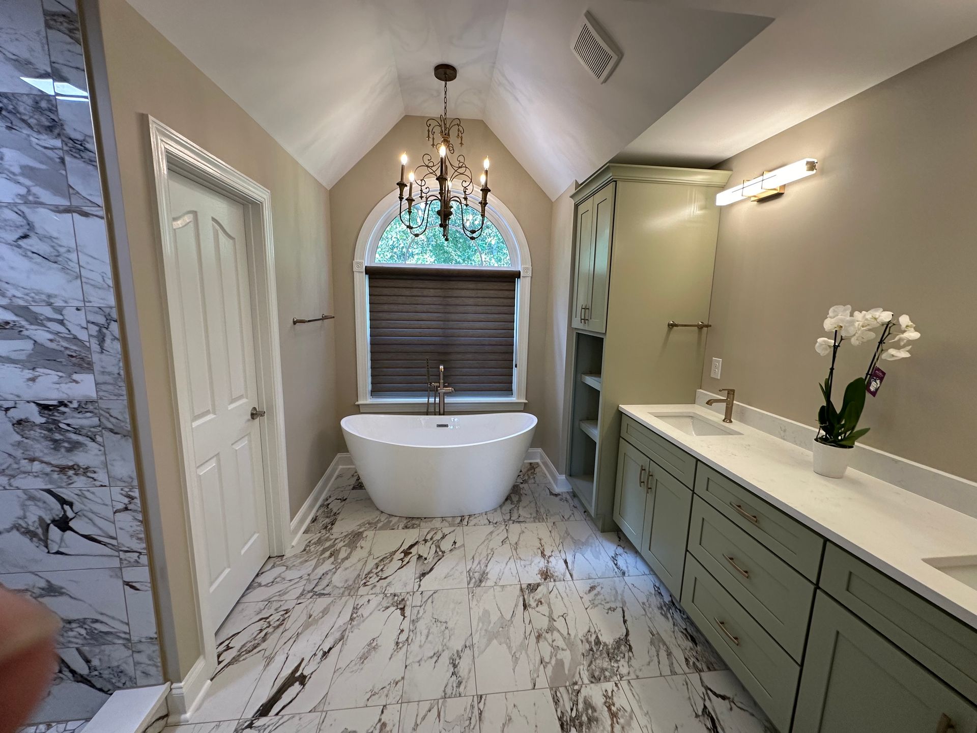 A bathroom with a bathtub , sinks , cabinets and a chandelier.