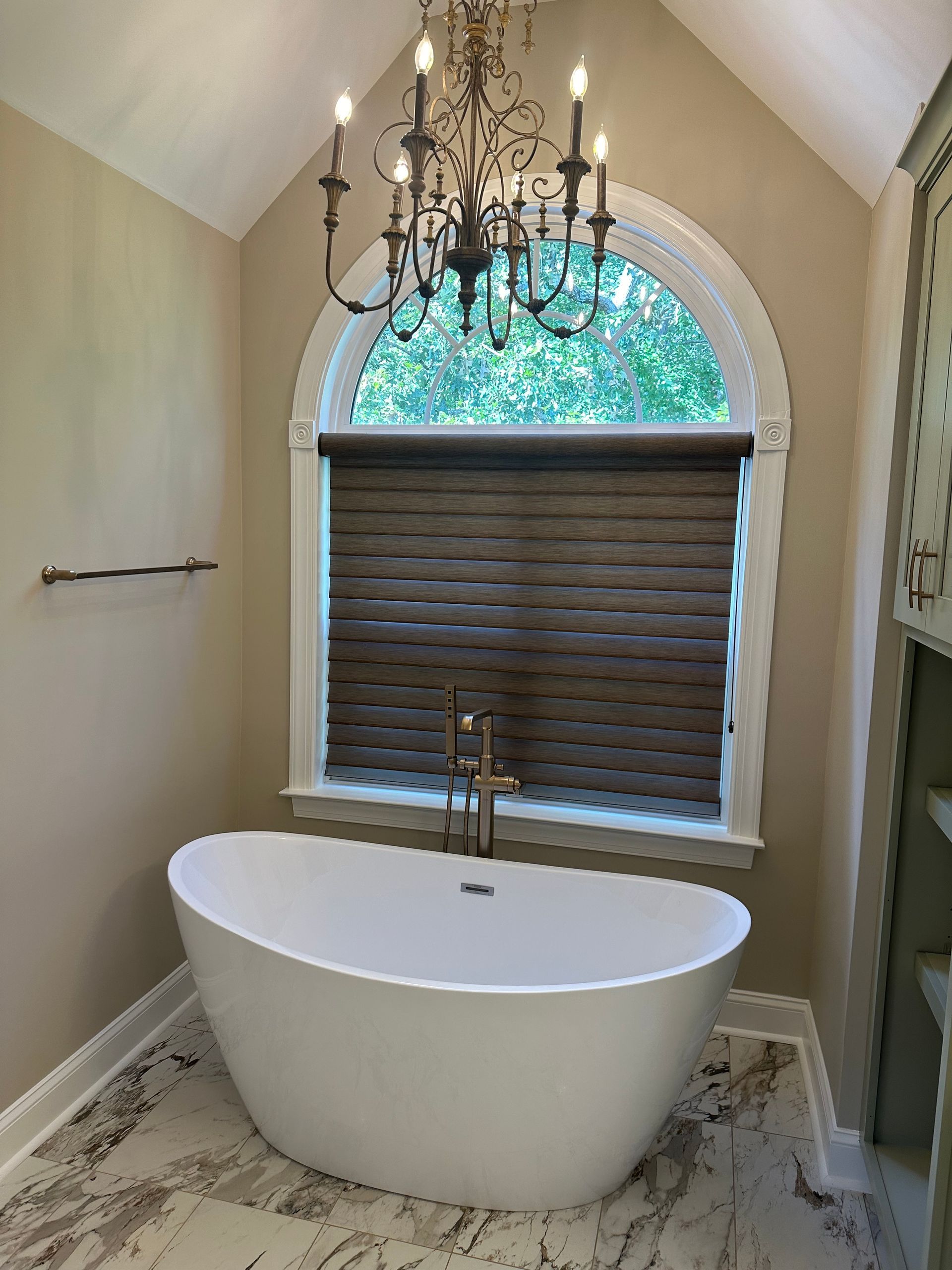 A bathroom with a bathtub and a chandelier hanging from the ceiling.