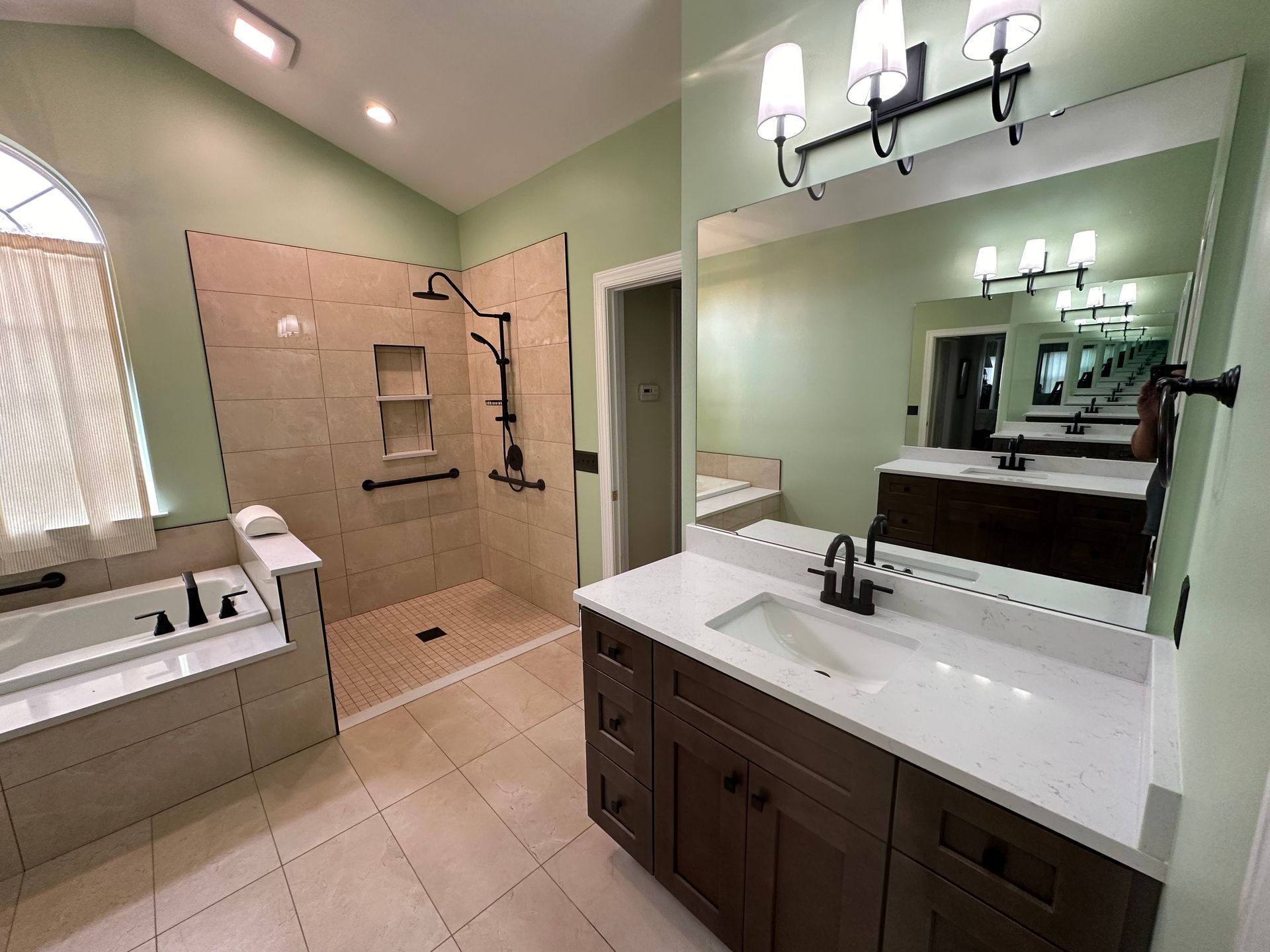 A bathroom with a sink , tub , shower and mirror.