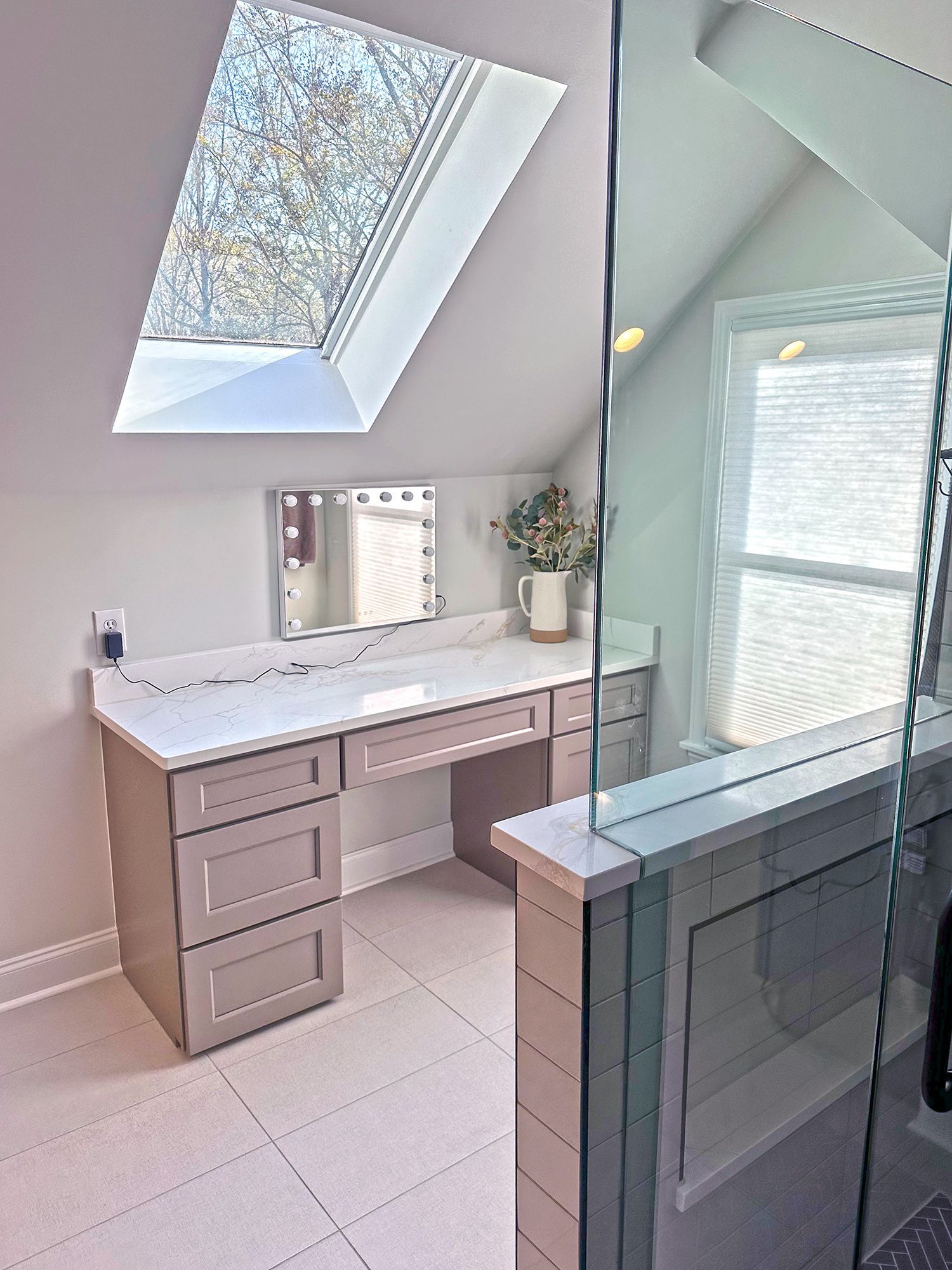 A bathroom with a vanity , mirror and skylight.