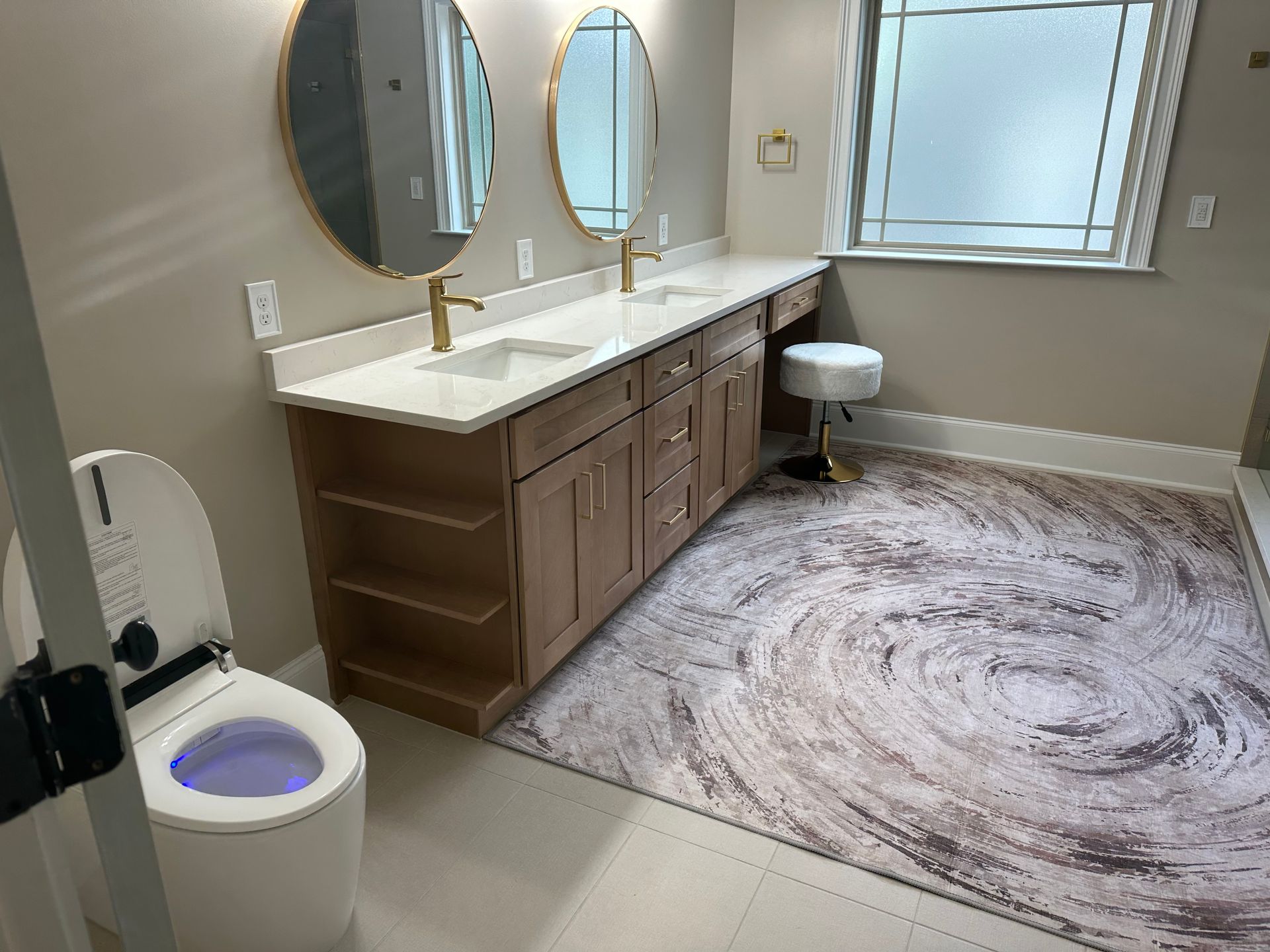 A bathroom with two sinks , a toilet , and a rug.